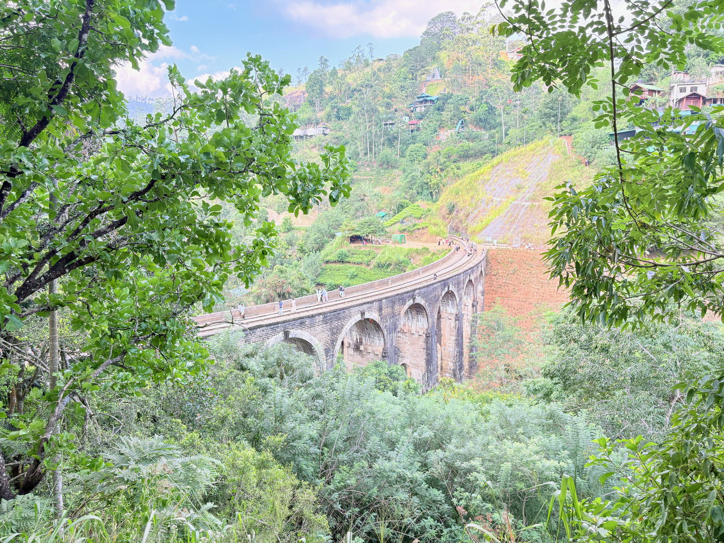 The Nine Arches Bridge curving away from the near end, its arches in raking light, red earth in the cutting at the right.