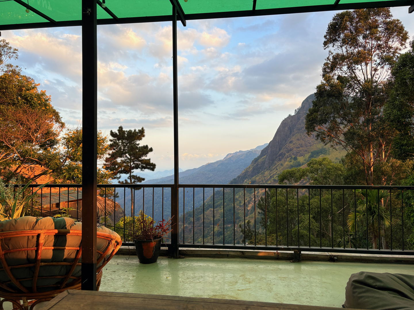 The terrace looking out: a railing, potted plants, and the mountain ridge across the valley in late light.